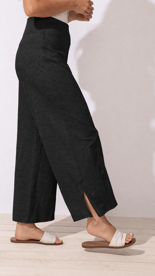 Person wearing black wide-leg pants on a plain background