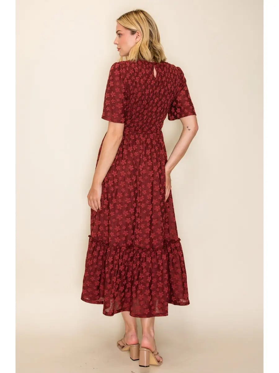 A woman modeling a dark red midi dress with a small floral pattern, shown from the back against a plain beige studio background.