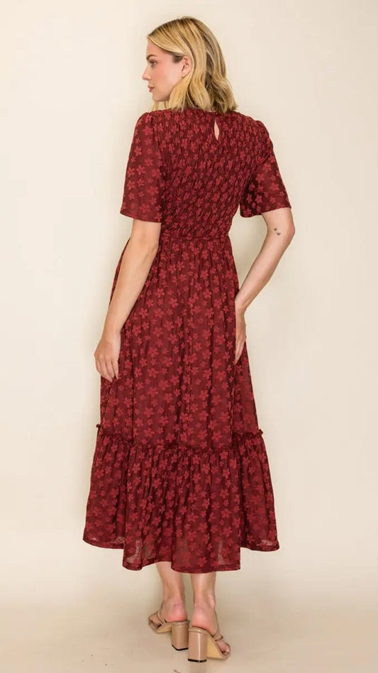 A woman modeling a dark red midi dress with a small floral pattern, shown from the back against a plain beige studio background.