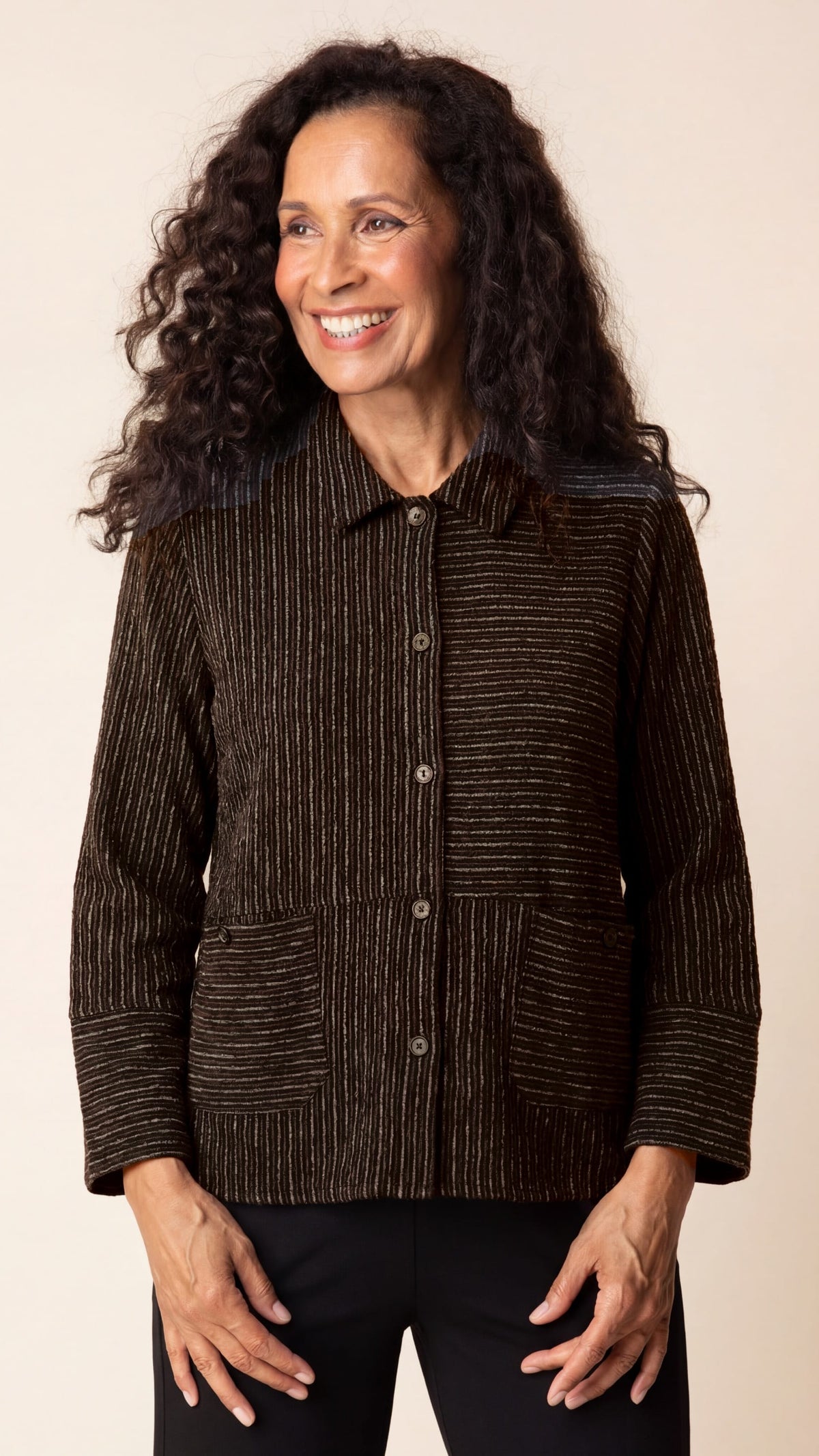 Woman wearing a brown textured jacket against a beige background
