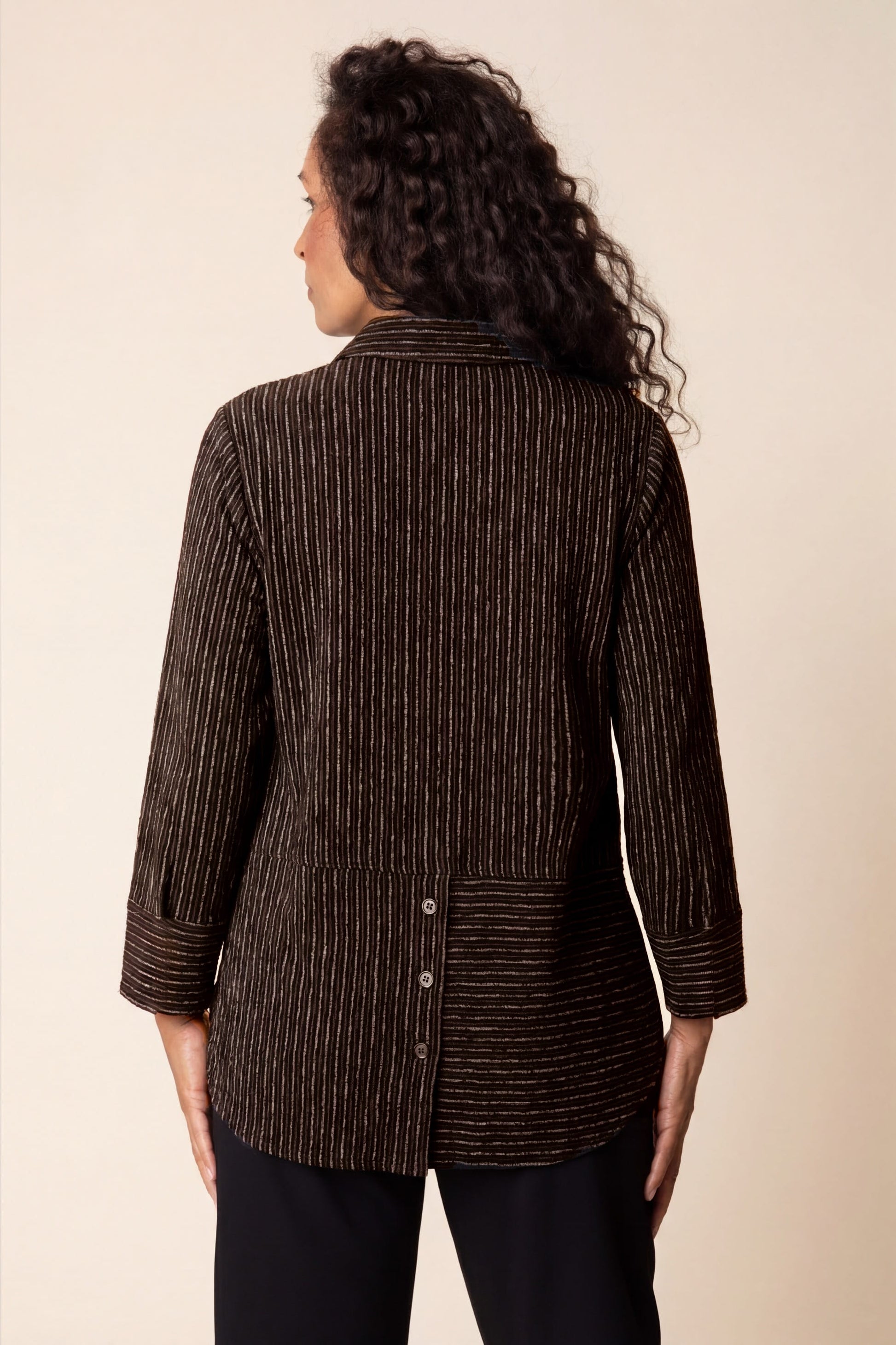 Woman wearing a brown pinstripe jacket against a beige background