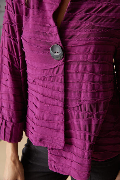 Close-up of a textured garment with a button on a neutral background