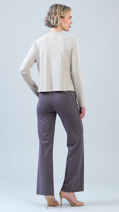 A woman is shown from the back wearing a light beige cropped long-sleeve cardigan and dark gray wide-leg pants, paired with nude high-heeled sandals, against a light gray studio background.