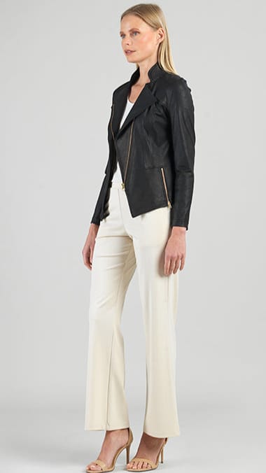 Woman wearing a black leather jacket and white pants on a gray background