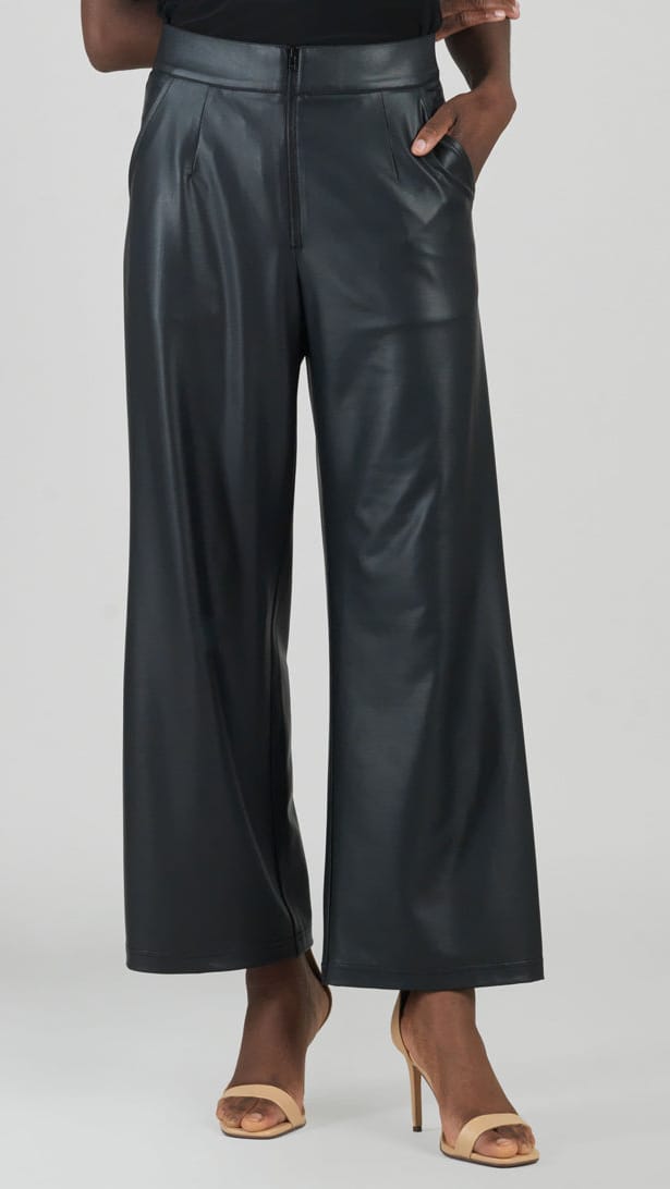 A model wearing black wide-leg faux leather pants with a high waist, paired with beige high-heeled sandals, shown from the waist down against a light gray studio background.