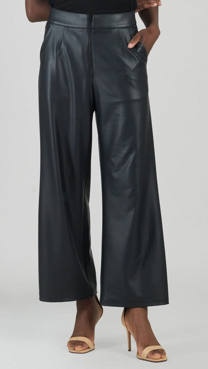 A model wearing black wide-leg faux leather pants with a high waist, paired with beige high-heeled sandals, shown from the waist down against a light gray studio background.