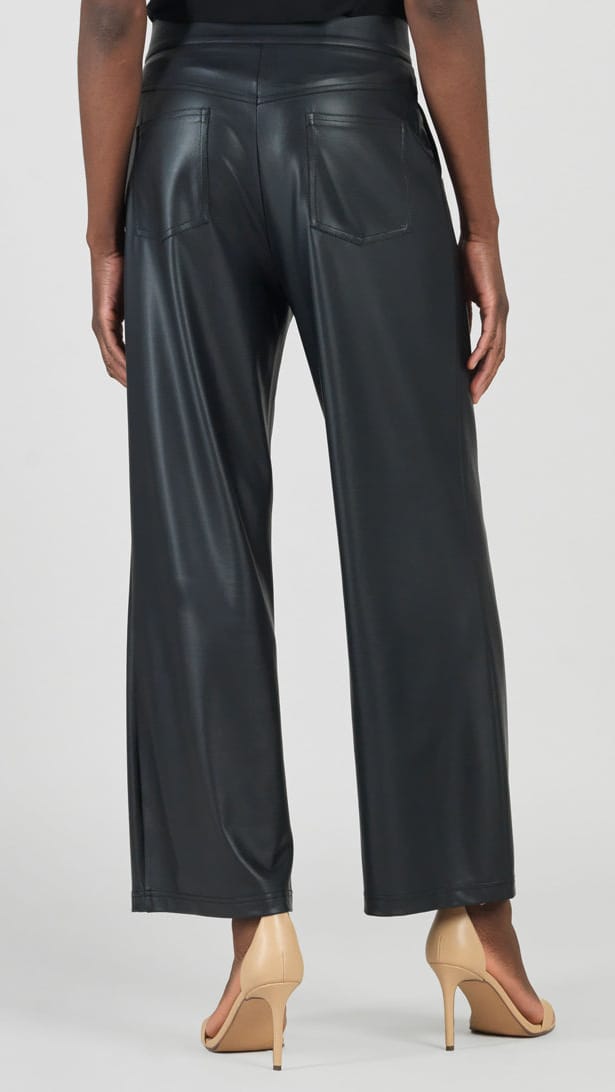 A model shown from the back wearing black wide-leg faux leather pants and beige high-heeled sandals against a light gray studio background.