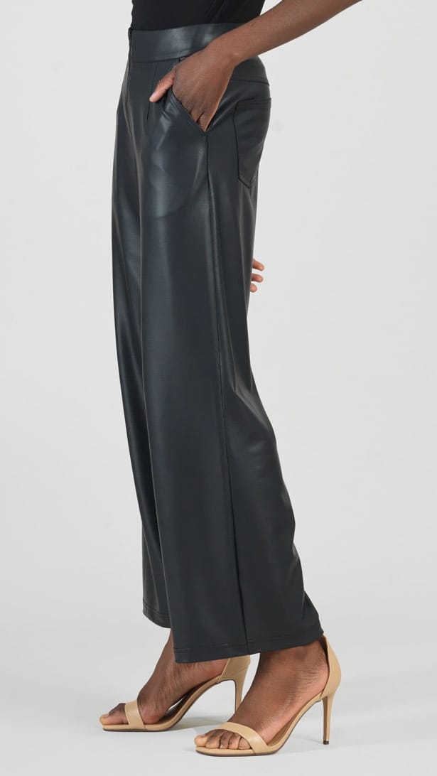 A model wearing black wide-leg faux leather pants with side pockets, paired with beige high-heeled sandals, shown from the waist down against a light gray studio background.