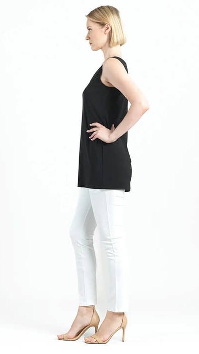 Woman wearing a black sleeveless top and white pants on a white background