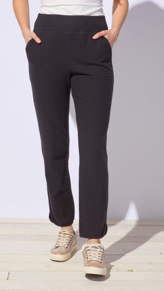 Person wearing black pants and beige sneakers on a white background