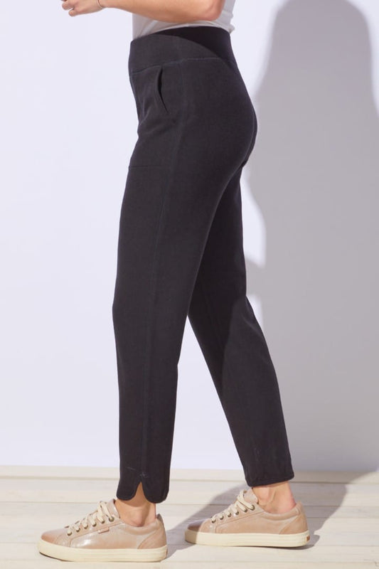 Person wearing black pants and beige shoes on a plain background