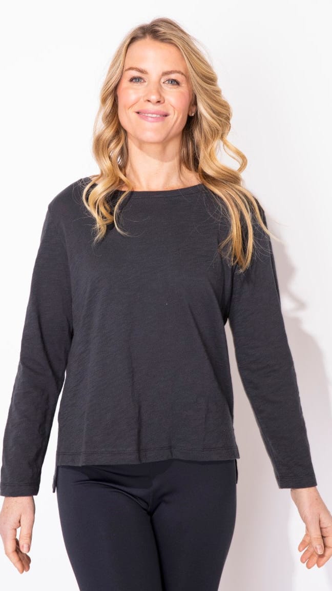 Woman wearing a black long-sleeve top and black pants on a white background