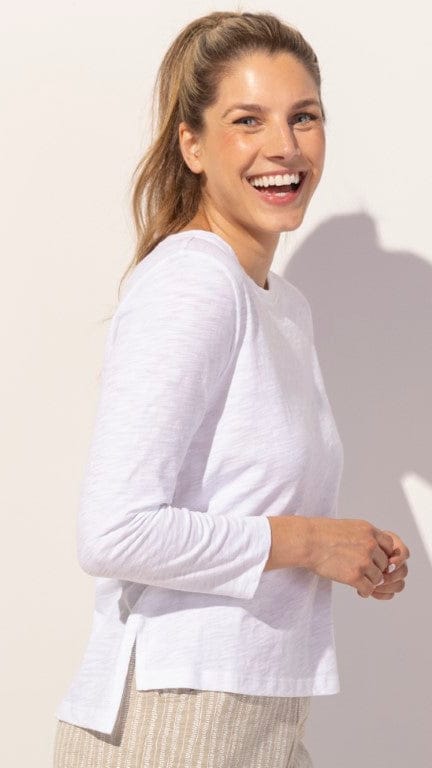 Woman wearing a white long-sleeve top against a light background