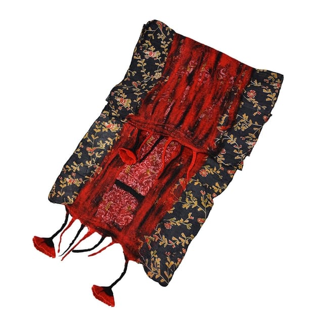A folded textile item, likely a decorative bag or pouch, featuring a black background with a gold floral pattern and a central red vertical stripe with red floral embroidery. The item has red tassels hanging from the bottom corners and is displayed on a solid white background.
