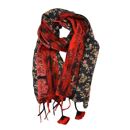 A lightweight scarf with a split design, featuring a vibrant red side with a subtle floral pattern and a black side with a gold floral print, finished with red tassels.