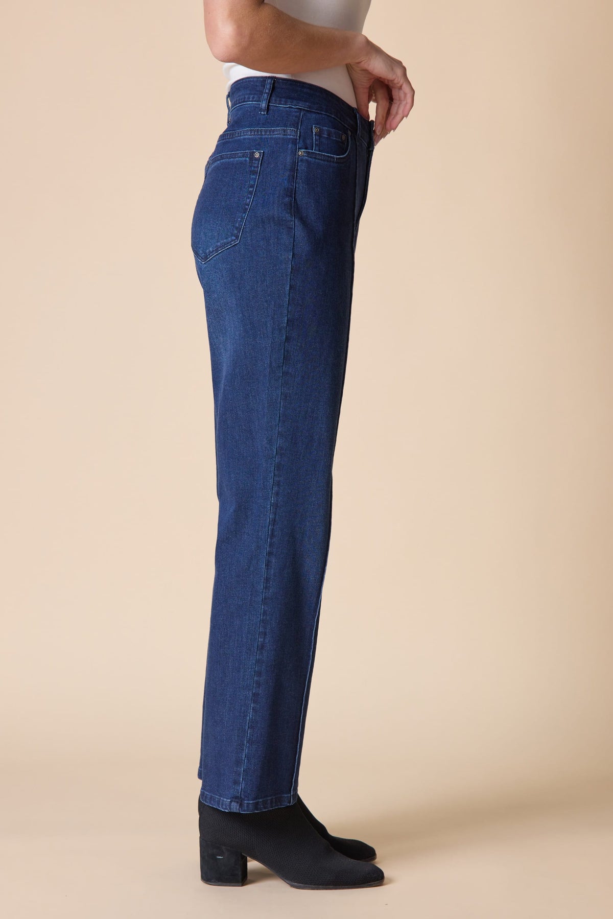 Person wearing blue jeans on a beige background