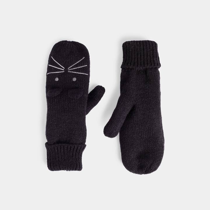 A pair of black knit mittens on a light gray background. One mitten features a white embroidered cat face design with whiskers and eyes, while the other is plain.