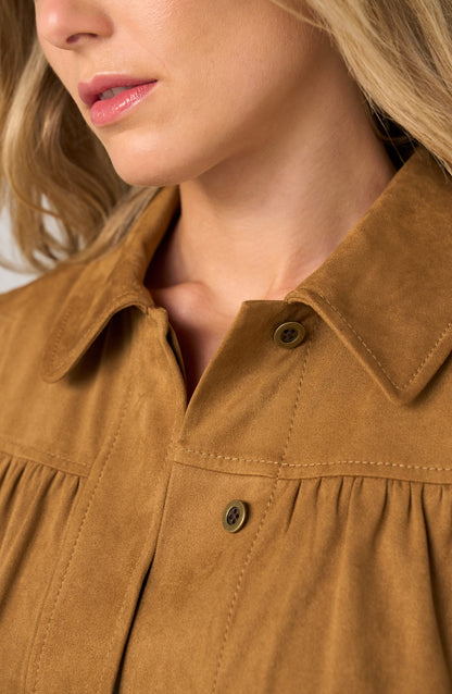 Close-up of a woman wearing a tan suede or faux-suede collared blouse with button front and gathered detailing.
