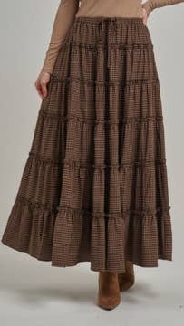 A brown tiered maxi skirt with a subtle plaid pattern, worn by a model with a beige top and brown boots against a plain light gray background.