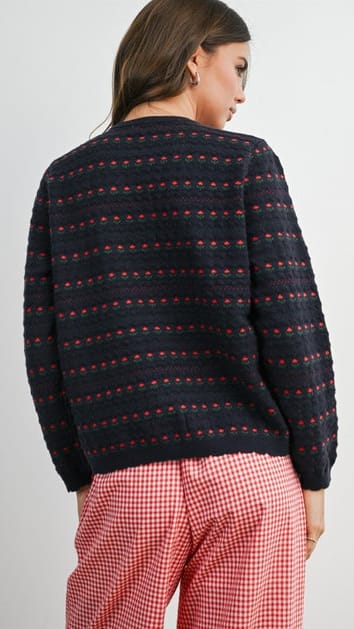A woman shown from the back wearing a dark navy knit sweater against a plain light gray studio background.