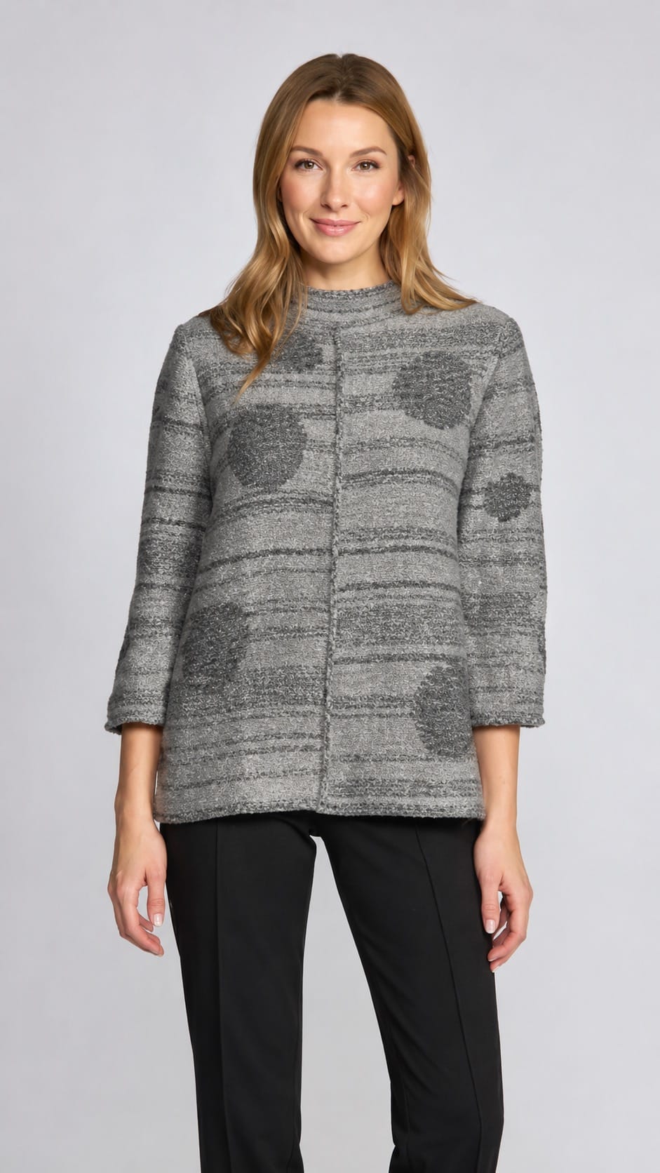 A woman modeling a gray textured knit cardigan with a high mock neck and three-quarter sleeves, paired with black pants, against a light gray studio background.