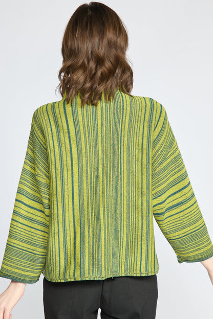 A woman viewed from the back wearing a cropped, wide-sleeved striped top in lime green and dark green, paired with black pants, against a light gray studio background.