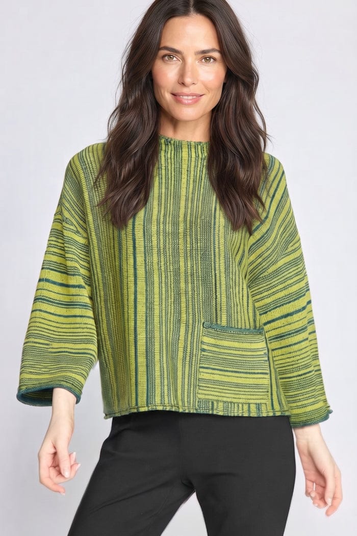 A woman modeling a green and yellow striped textured top with three-quarter sleeves and a front patch pocket, paired with black pants, against a light gray studio background.