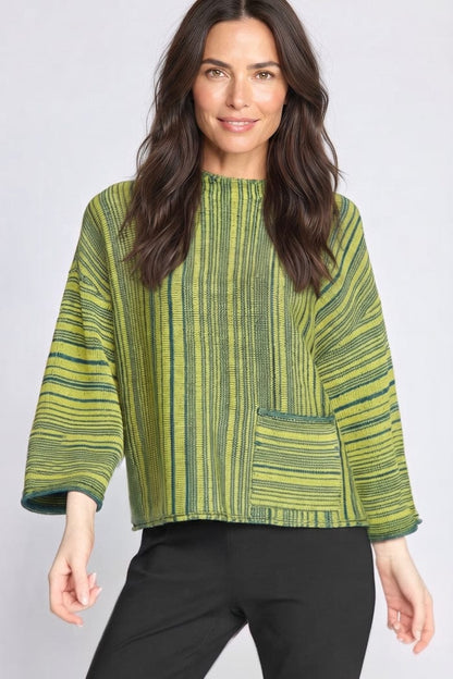 A woman modeling a green and yellow striped textured top with three-quarter sleeves and a front patch pocket, paired with black pants, against a light gray studio background.