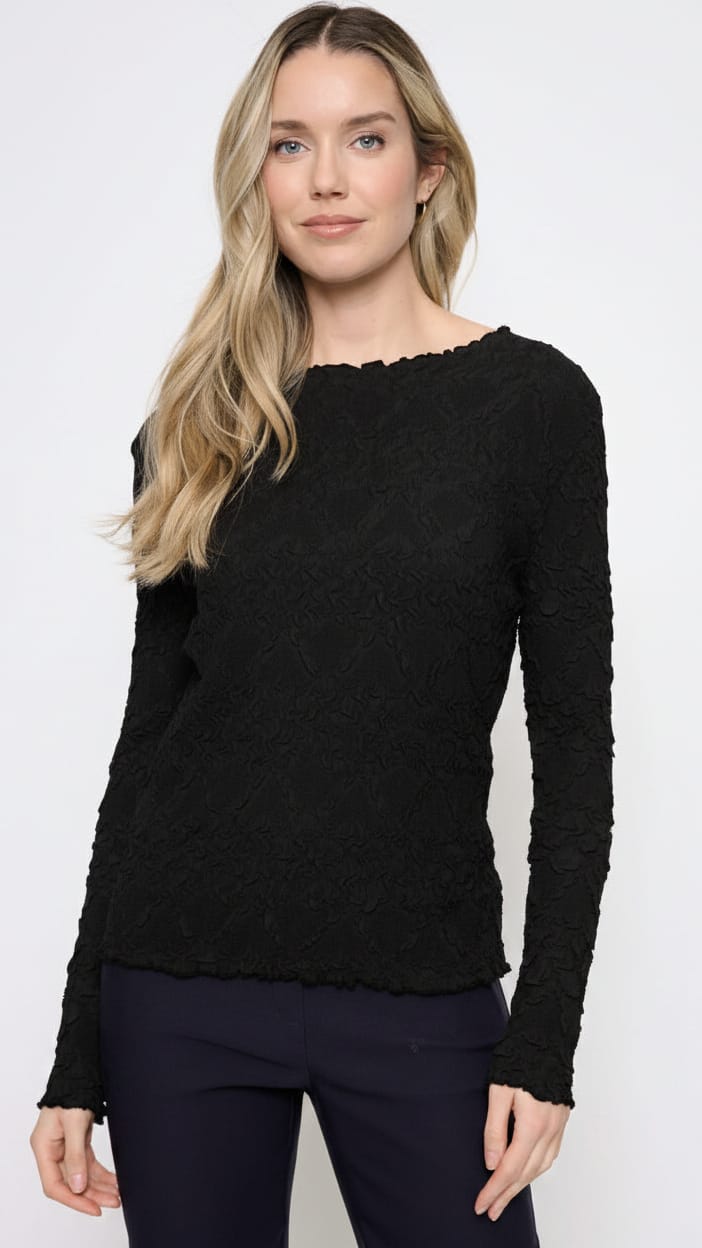 A woman modeling a navy blue long-sleeve textured knit top with a scalloped neckline, paired with black pants, against a plain white studio background.