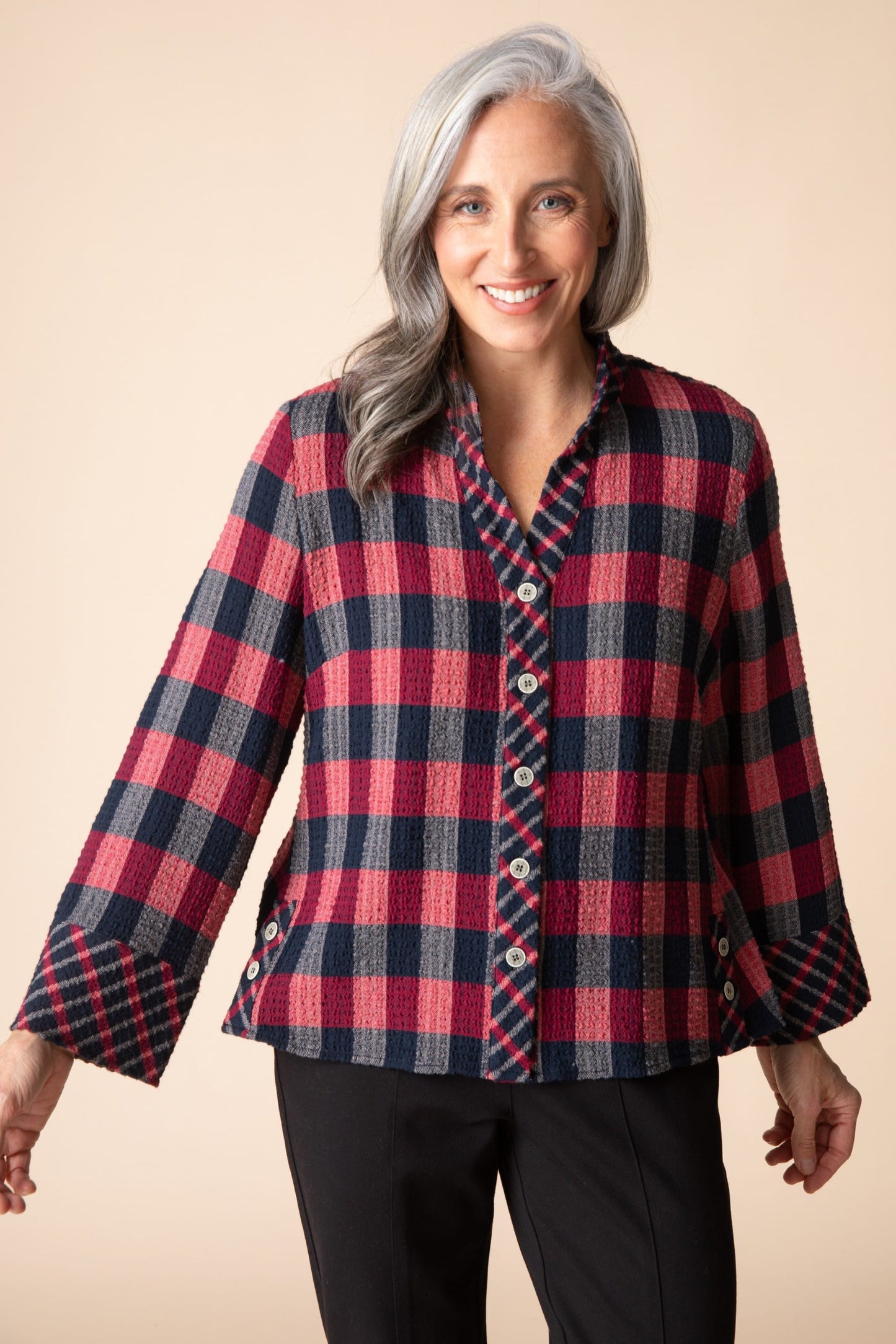 Woman wearing a red and blue plaid shirt against a beige background