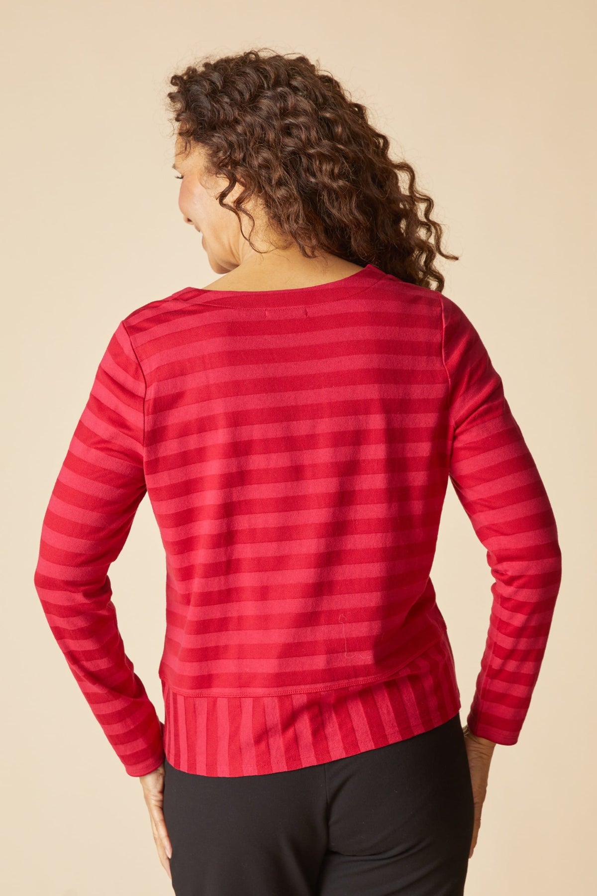 Person wearing a red striped top against a beige background