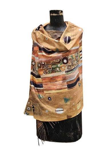 A multicolor scarf with an art-deco style pattern in shades of gold, brown, beige, and black, draped on a black mannequin torso against a white background.
