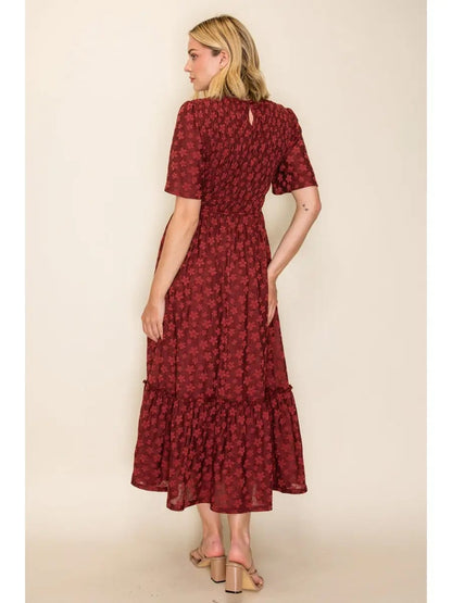A woman modeling a dark red midi dress with a small floral pattern, shown from the back against a plain beige studio background.
