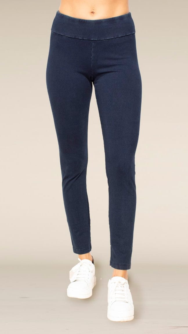 A person wearing dark navy blue leggings and white sneakers, shown from the waist down against a plain light beige studio background.