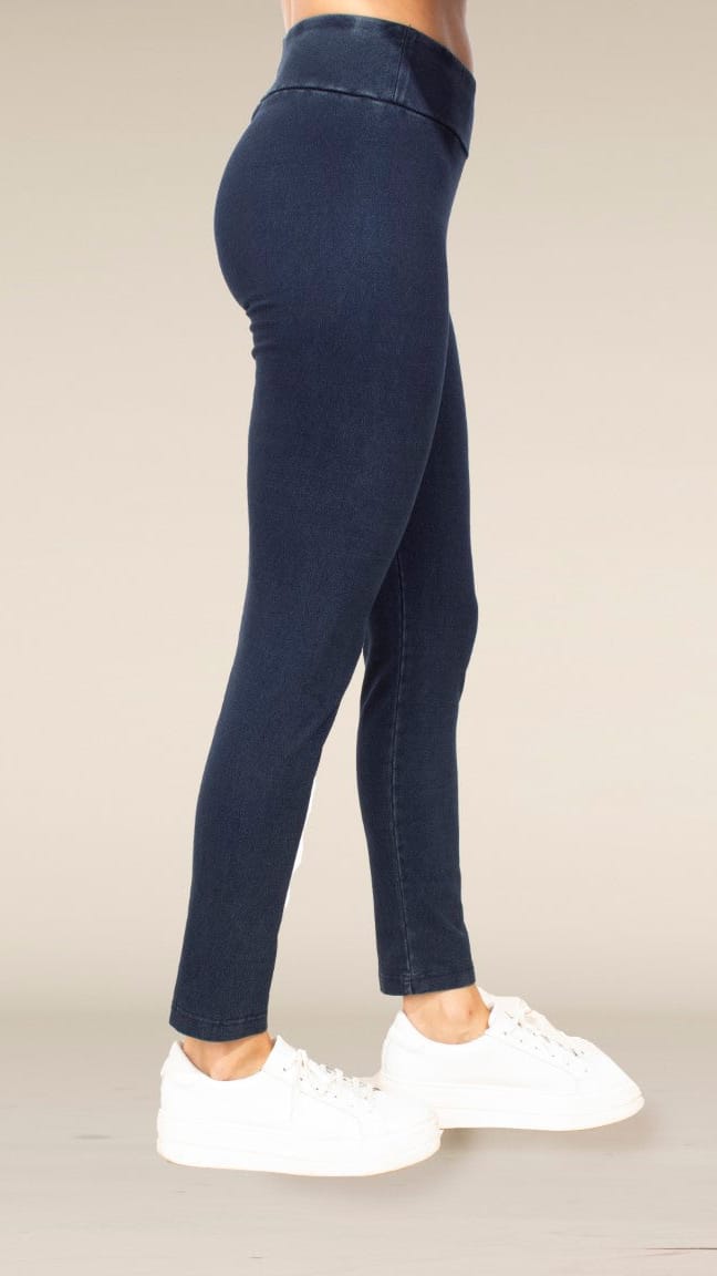 A person shown from the waist down wearing dark navy blue skinny leggings and white platform sneakers against a plain beige studio background.