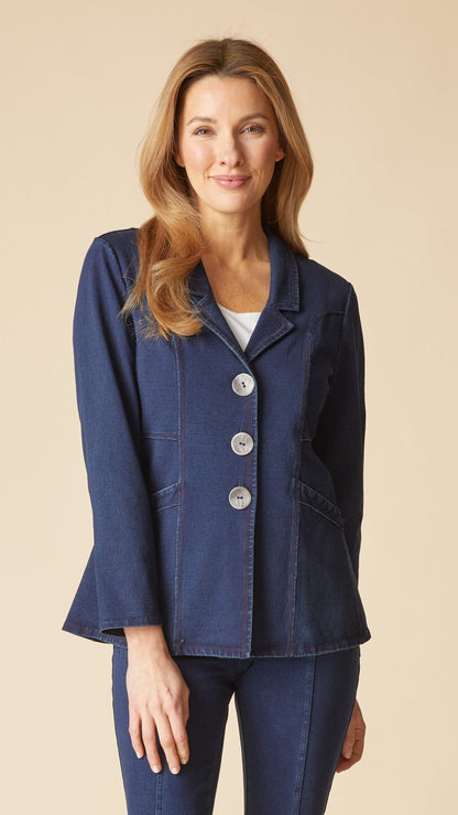 A woman modeling a dark blue denim-style blazer with three large front buttons, paired with matching blue jeans, against a solid beige background.