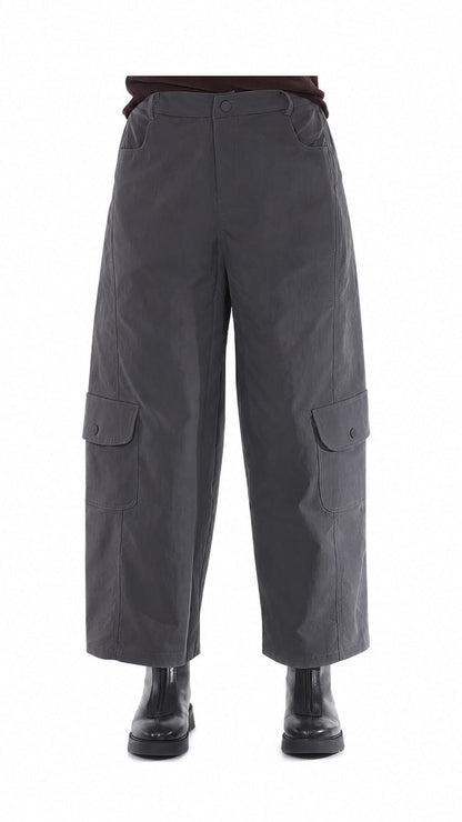 Dark gray wide-leg cargo pants with large flap pockets on the lower legs, shown on a white background with black boots and a dark top partially visible.