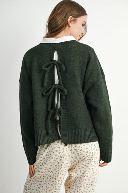 Green sweater with bow details on the back worn by a person on a white background