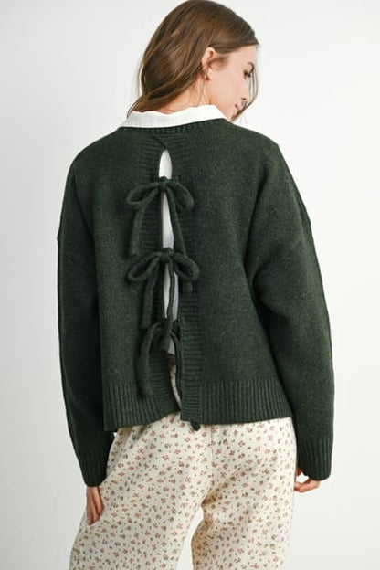 Green sweater with bow details on the back worn by a person on a white background