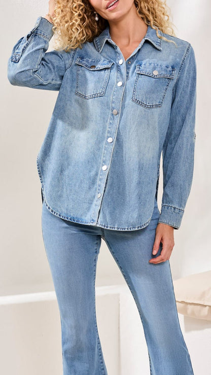 Woman wearing a light blue denim shirt and jeans on a white background
