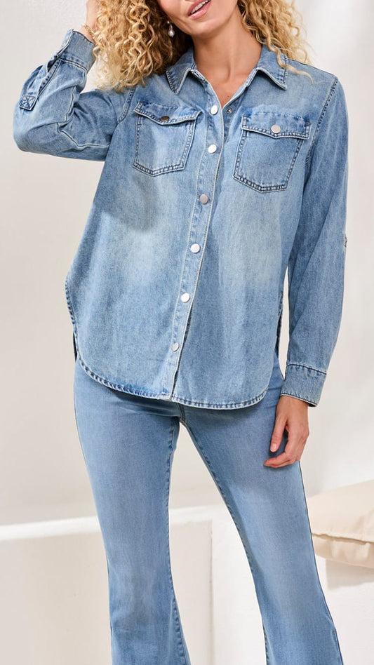 Woman wearing a light blue denim shirt and jeans on a white background