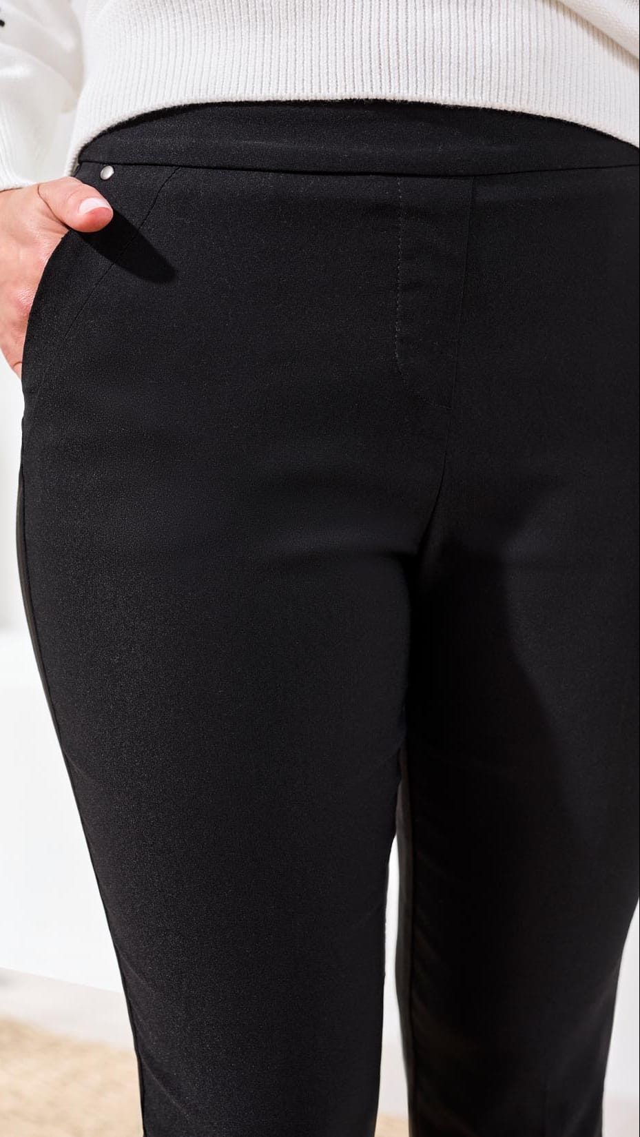 Black pants with a close-up of the waistband against a neutral background