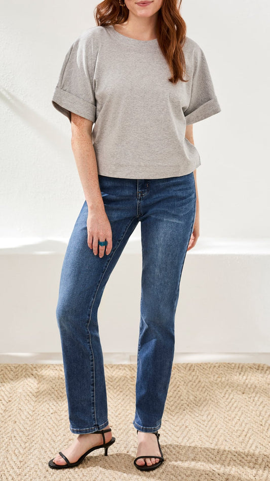 Person wearing a gray oversized shirt and blue jeans on a white background