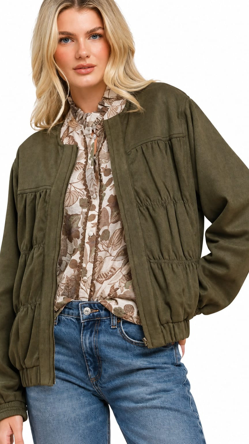 A woman wearing an olive green cropped jacket with gathered details over a beige and brown floral print blouse and blue jeans, set against a plain white background.