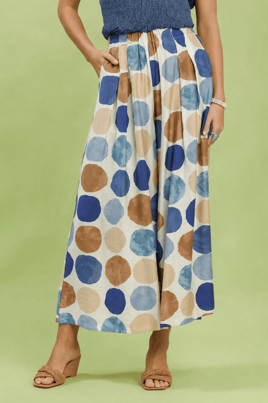 Person wearing a patterned skirt with blue, brown, and beige circles on a green background