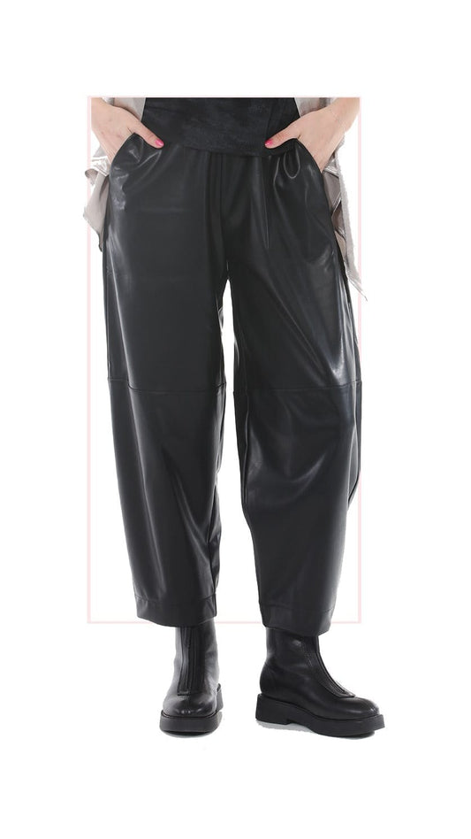 Black faux leather pants with a drawstring waist and side pockets, shown on a model from the waist down wearing black boots against a white background.