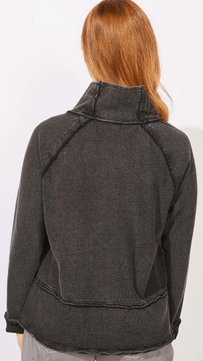 A person shown from the back wearing a dark charcoal gray cropped raglan sweatshirt or lightweight jacket with a high mock neck collar, set against a plain white background.